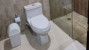 A bathroom with a toilet, bidet, and a glass-enclosed shower area. - Casa Yaxche (Valladolid)