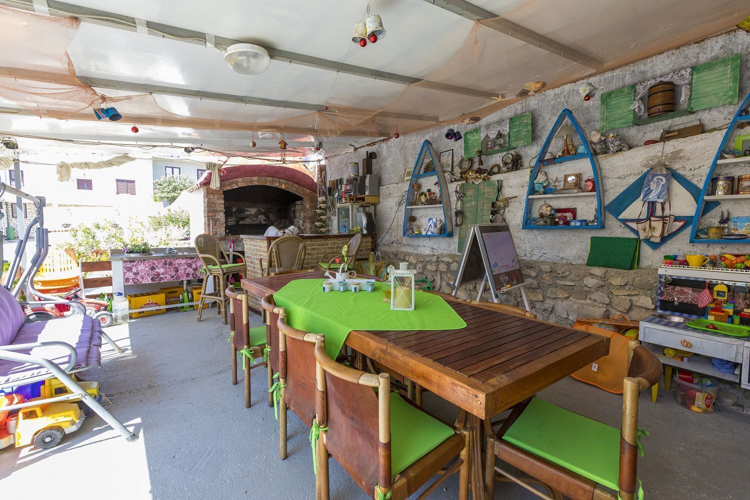 Un espacio de comedor al aire libre con horno de ladrillo, mesas y sillas de madera.