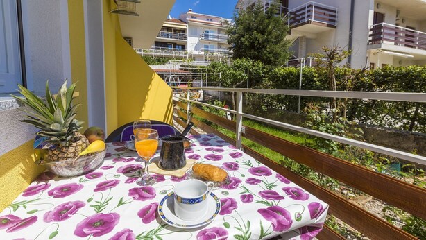 A balcony with a table set for breakfast, including fruits, a glass of orange juice, and a cup. - Charming dog-friendly flat with private balcony, playground, barbecue (Crikvenica)