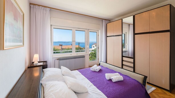 Ein Schlafzimmer mit Bett, Fenster mit Blick, Heizkörper und Kleiderschrank.