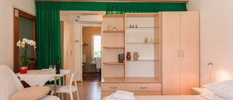 Una camera d'albergo con un letto, una scrivania con sedia, un armadio e un'area pranzo.
