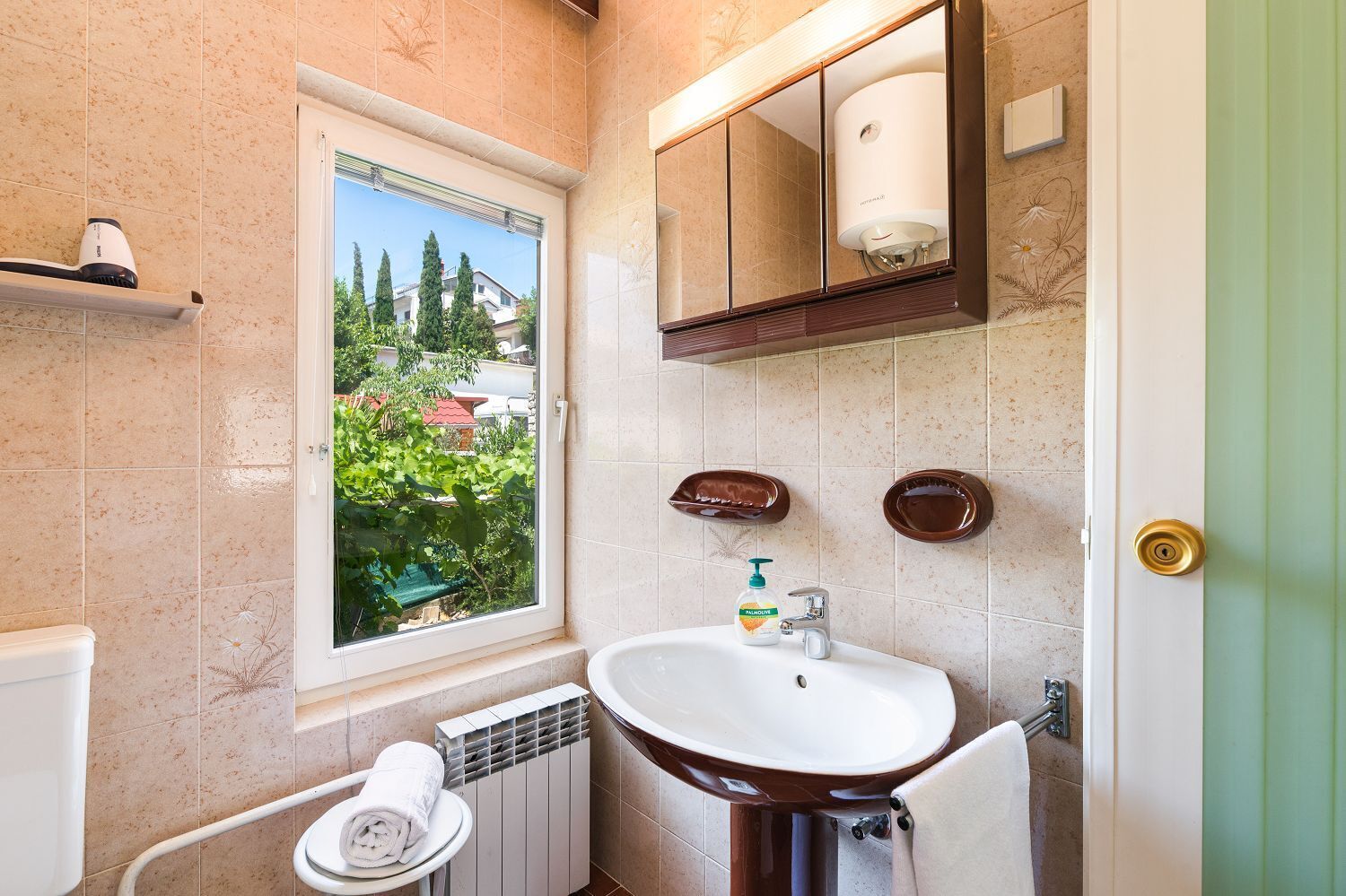 Une salle de bain avec une fenêtre, un lavabo, des toilettes et un porte-serviettes.