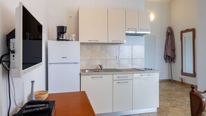 Una cocina compacta con armarios blancos, horno integrado y un lavabo.