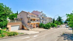 Una calle residencial con edificios de varios pisos, cielo despejado y algunos coches estacionados a lo largo de la vía.