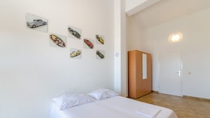 A bedroom with a bed, a wardrobe, and wall art of cars.