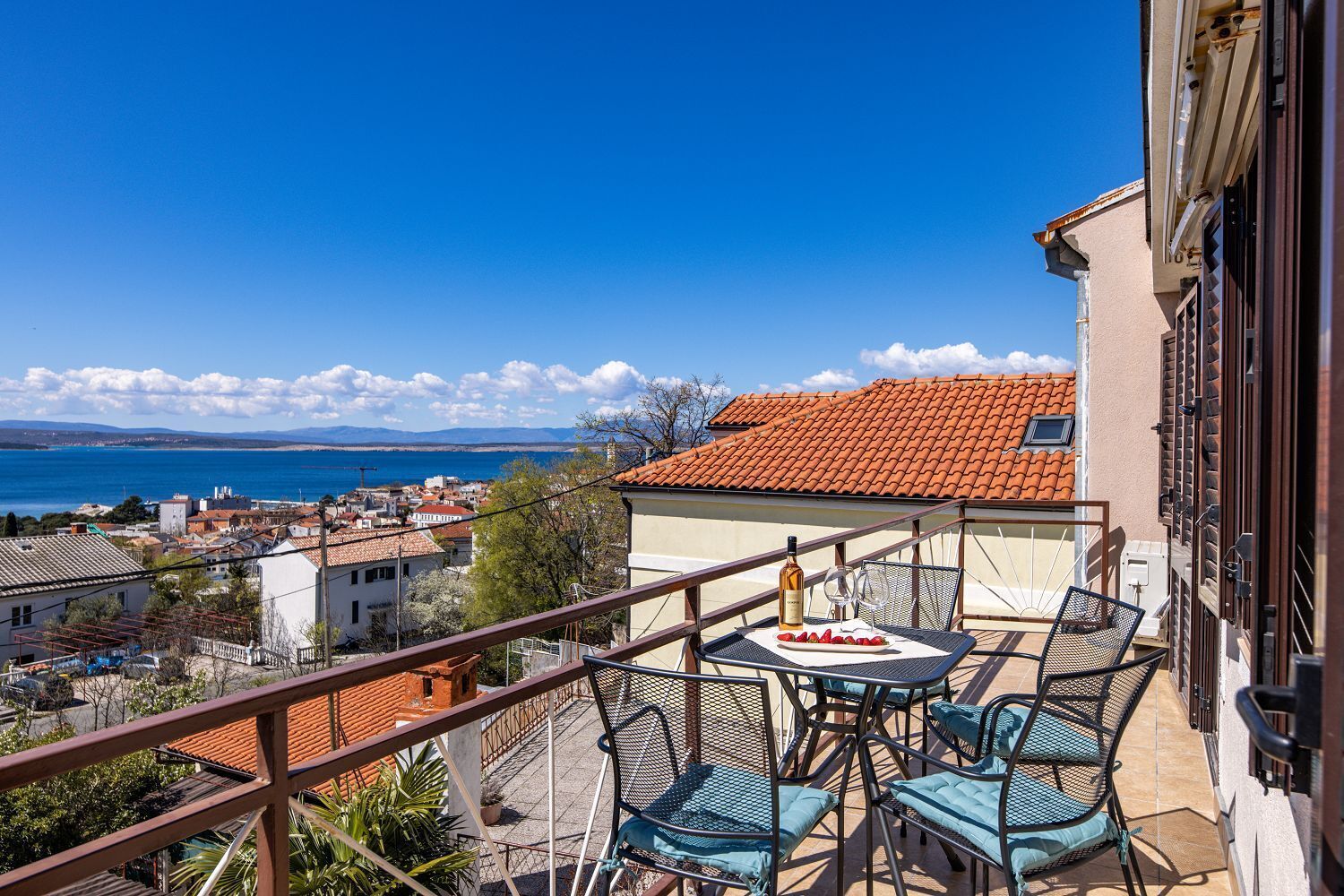 En balkon med havemøbler, en vinflaske og et fad med jordbær.