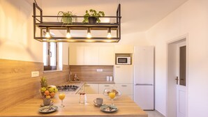 A modern kitchen with a wooden island, white cabinets, a microwave, and a refrigerator.