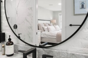 A bathroom with a marble floor, a black circular mirror, a bottle of lotion, and a towel rack. - Amazing 3 Bedroom 3 Bath, Fully Renovated, Central Andover Location (Andover)