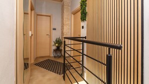 A hallway with a wooden door, a small potted plant, a black metal railing, and a stone wall. - Fascinating holiday home just 500 metres from the beach with sea views, whirlpool, barbecue (Dramalj)