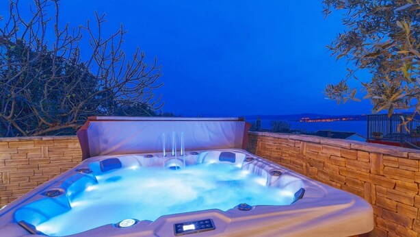 A hot tub with a control panel, set against a stone wall with a view of the sea and trees. - Fascinating holiday home just 500 metres from the beach with sea views, whirlpool, barbecue (Dramalj)