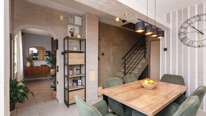 A modern dining area with a wooden table, green upholstered chairs, and a decorative clock on the wall. - Fascinating holiday home just 500 metres from the beach with sea views, whirlpool, barbecue (Dramalj)