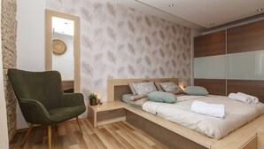 A modern bedroom with a wooden bed, a green armchair, and a wall with a feather pattern. - Fascinating holiday home just 500 metres from the beach with sea views, whirlpool, barbecue (Dramalj)