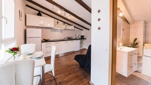 A modern kitchen with white cabinets, a dining area with a white table and chairs, and a visible bathroom with a sink and towel rack. - Impressive flat just 500 metres from the beach with sea views, flat-screen TV on the balcony, BBQ (Dramalj)