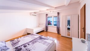 A bedroom with a bed, a small bedside table, a wardrobe, and a window with curtains. - Impressive flat just 500 metres from the beach with sea views, flat-screen TV on the balcony, BBQ (Dramalj)
