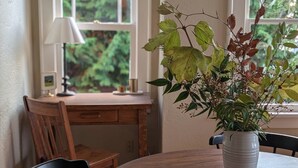 En matplats med ett runt bord, två stolar, en krukväxt och ett skrivbord med en lampa.