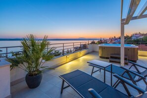 Enjoy breathtaking views of the water from this rooftop terrace, featuring a seating area and hot tub.