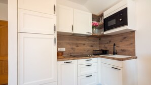 Uma cozinha compacta com armários brancos, painel de backsplash de madeira, micro-ondas e pia.