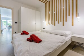 A modern hotel room with a large bed, a desk, and a view of the outdoors.