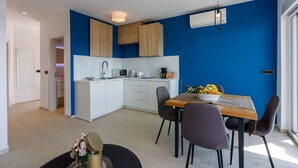 A modern kitchen with white cabinets, a microwave, and a coffee maker. There is a dining table with chairs and a bowl of fruit. - Impressive flat just 500 metres from the beach with sea views, sauna, gym, pool (Crikvenica)