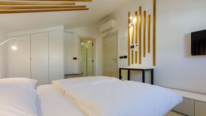 A modern hotel room with a large bed, a bedside table, a wardrobe, and a shower area. - Exquisite flat with sea view, sauna, gym, pool, air-conditioned bedrooms - only 500 metres to the beach (Crikvenica)