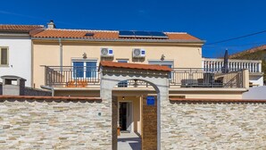 Edifici amb façana de pedra, un balcó amb barana i un senyal que indica una qualificació de 5 estrelles.