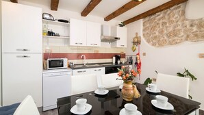 Cuina moderna amb armaris blancs, microones i un rentaplat. Hi ha una taula de menjador amb plats i un vas de flors.