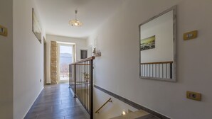 Un passadís amb una escala, una porta que dona a l'exterior i una làmpada de paret.