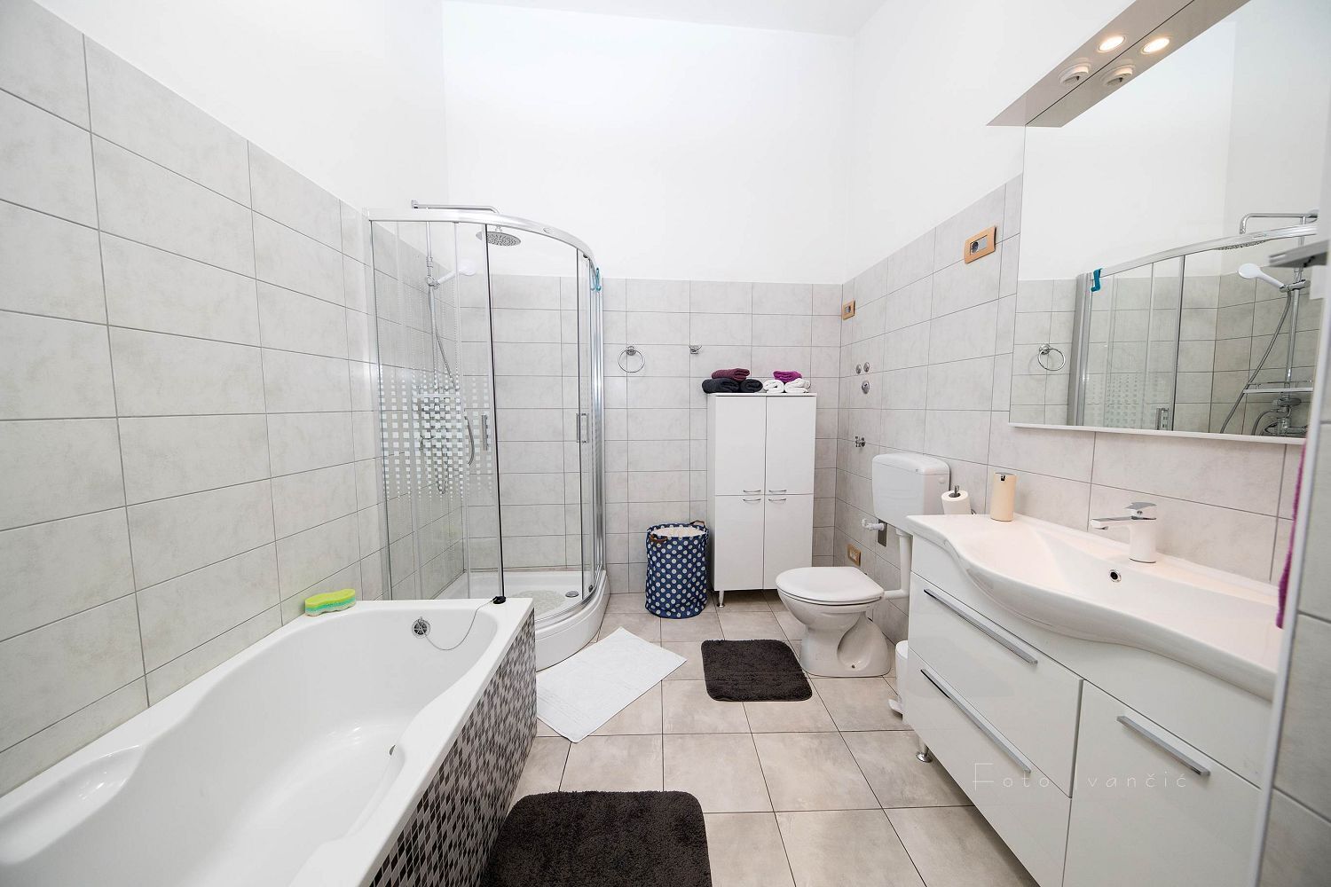 A modern bathroom with a glass-enclosed shower, a white toilet, and a sink with a mirror.