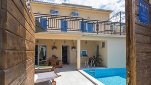 Hotel amb piscina, zones d'estar a l'exterior i un balcó amb aparells d'aire condicionat.