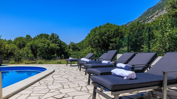 A poolside area with lounge chairs and a swimming pool. - Stunning villa with whirlpool, private pool, outdoor shower, fitness room, washing machine (Tribalj)