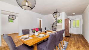 A dining area with a wooden table set for six, surrounded by purple chairs, with a staircase in the background. - Stunning villa with whirlpool, private pool, outdoor shower, fitness room, washing machine (Tribalj)