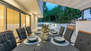 A dining area with a table set for six, surrounded by chairs, and a view of a lush garden.