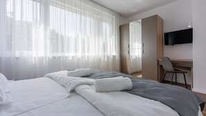 A hotel room with a bed, a desk, and a TV.