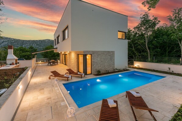 Relax by the pool surrounded by a patio with lounge chairs and a table.
