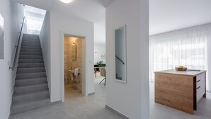 A modern interior with a staircase leading to a bathroom, a wooden desk, and a mirror.