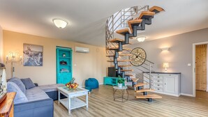 A modern living room with a spiral staircase, a sofa set, a coffee table, and a teal cabinet. - Villa Leticija (Hreljin)