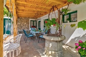 Relax in a serene outdoor space with a stone wall, wooden ceiling, and comfortable seating for two.
