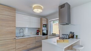 Una cocina moderna con armarios de madera, horno empotrado, cafetera y ventana con vistas.