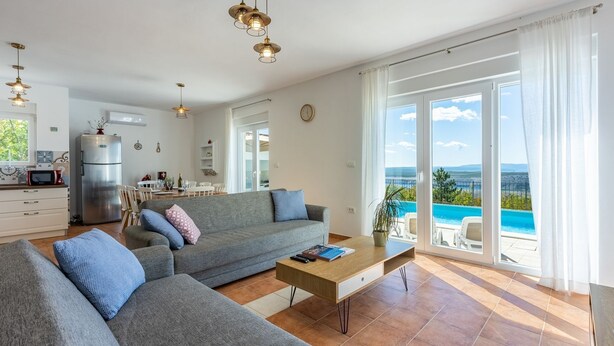 Un salón moderno con un sofá gris, una mesa de centro y vistas a una piscina.