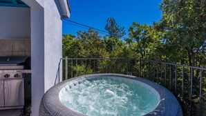 Un jacuzzi al aire libre con una parrilla de acero inoxidable y un patio con baldosas.