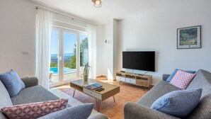 Una sala de estar moderna con un televisor de pantalla plana, sofás grises y una mesa de centro.