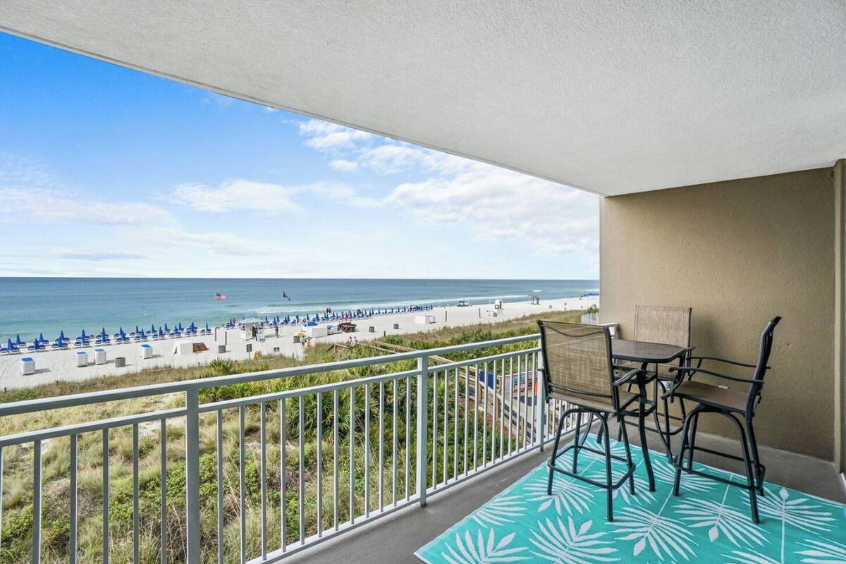 Ein Balkon mit Blick auf den Strand, inklusive Tisch und Stühlen.