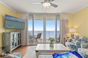 Relax in this stylish living room with a sofa, coffee table, and glass-front cabinet, offering a view of the ocean from the balcony.