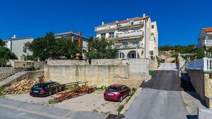 Zona residenziale caratterizzata da un edificio a più piani, muri in pietra e auto parcheggiate.