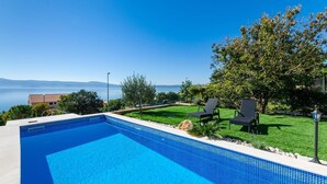 Una piscina con vista chiara sul mare e sulle montagne sullo sfondo.