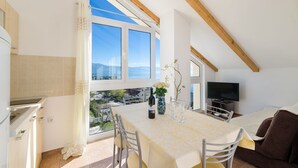 Zona pranzo con tavolo imbandito per quattro persone, televisione e vista sul paesaggio.
