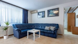 Un salon moderne avec un canapé en cuir bleu, une table basse blanche et une plante en pot.