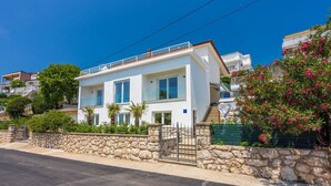 Une maison moderne à deux étages, dotée d’un mur en pierre et d’un portail en métal.