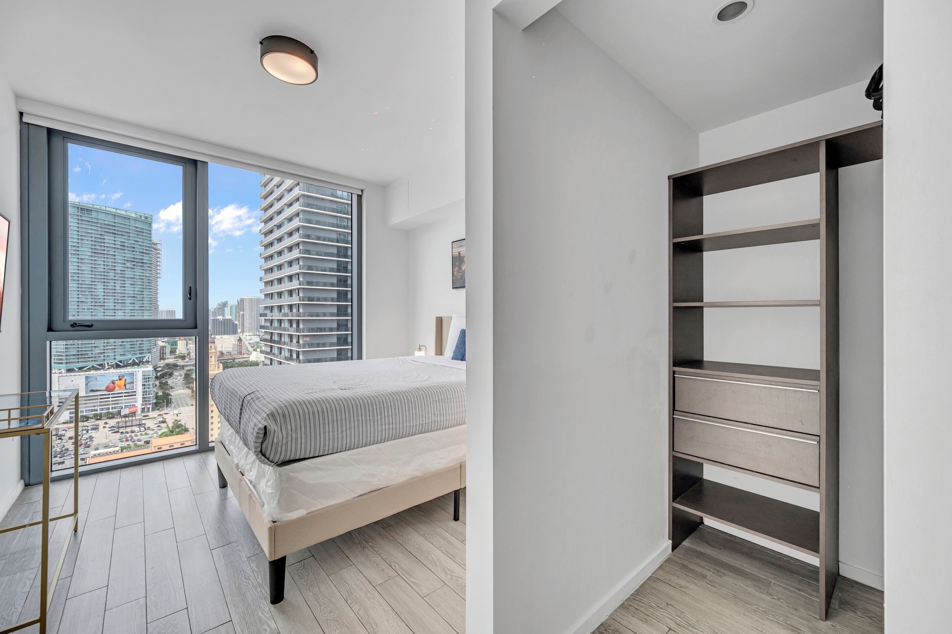 Un dormitorio moderno con un ventanal grande, una cama y un armario empotrado.