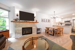 A modern living room with a fireplace, a dining area, and a kitchen.